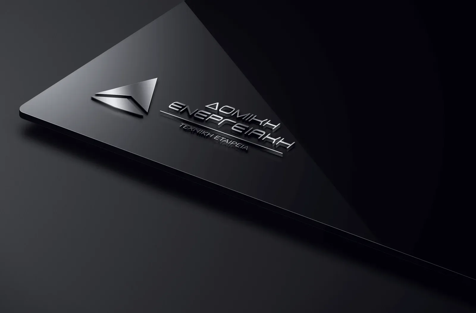The Domiki Energeiaki logo rendered in brushed metal on a black signage plaque