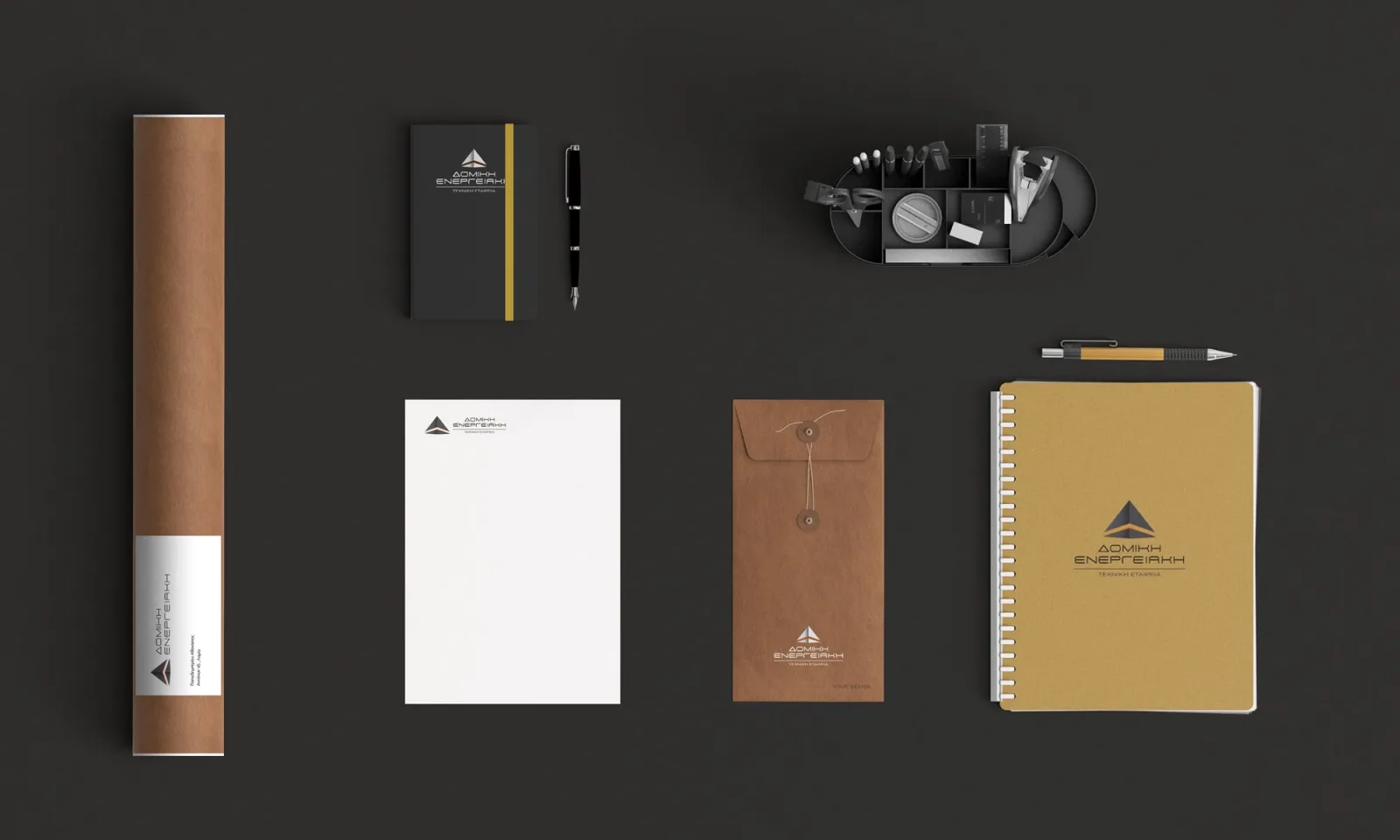 Domiki Energeiaki stationery flatlay — drawing tube, notebook, letterhead, string-tie envelope and spiral notepad